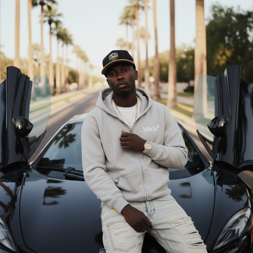 Model wearing a gray "Made®" zip-up hoodie. 